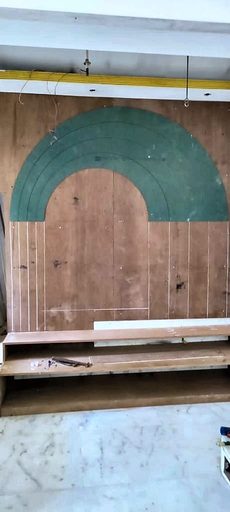 The mandir arch as raw plywood, cut to shape and propped against an unfinished wall.