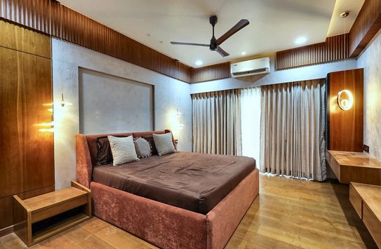 The terracotta bedroom seen wider — the bed on the left, a built-in desk and mirror running along the wall to the right.