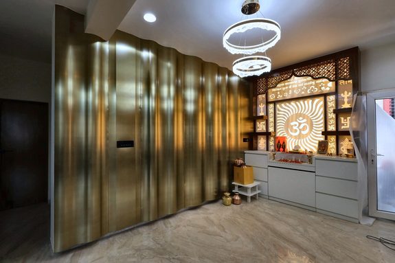 The dining wall built — brass fluting the full height of the room, and a backlit jaali shrine beside it.