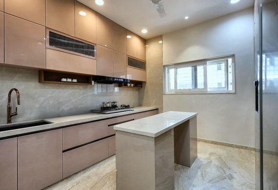 The kitchen built — the same run of cabinets, in blush laminate, with the island standing where the drawing put it.