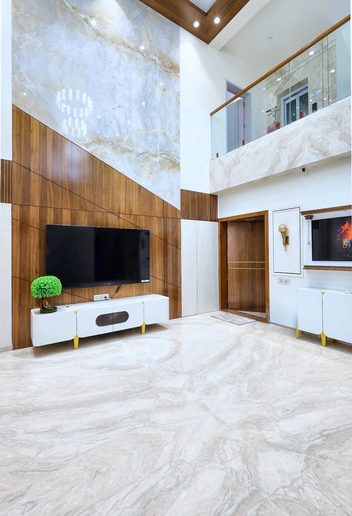 The same wall finished — a full-height stone panel crossed by a diagonal band of teak, the television set into it, a white console below.