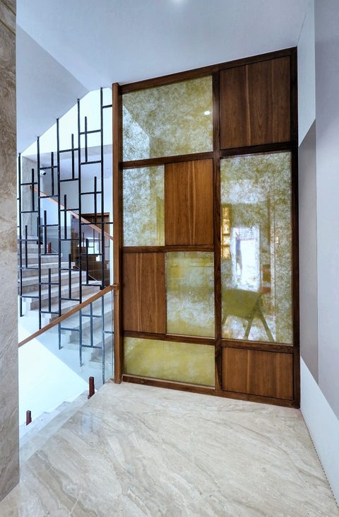 A timber-framed screen of backlit onyx panels standing beside the staircase.